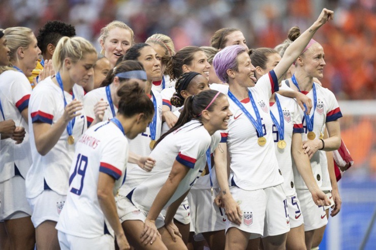Megan Rapinoe (hàng trước, tóc vàng, giơ tay) cùng đội đội của tuyển Mỹ là những người tiên phong trong việc bình đẳng giới về thu nhập trong thể thao. Ảnh: Getty
