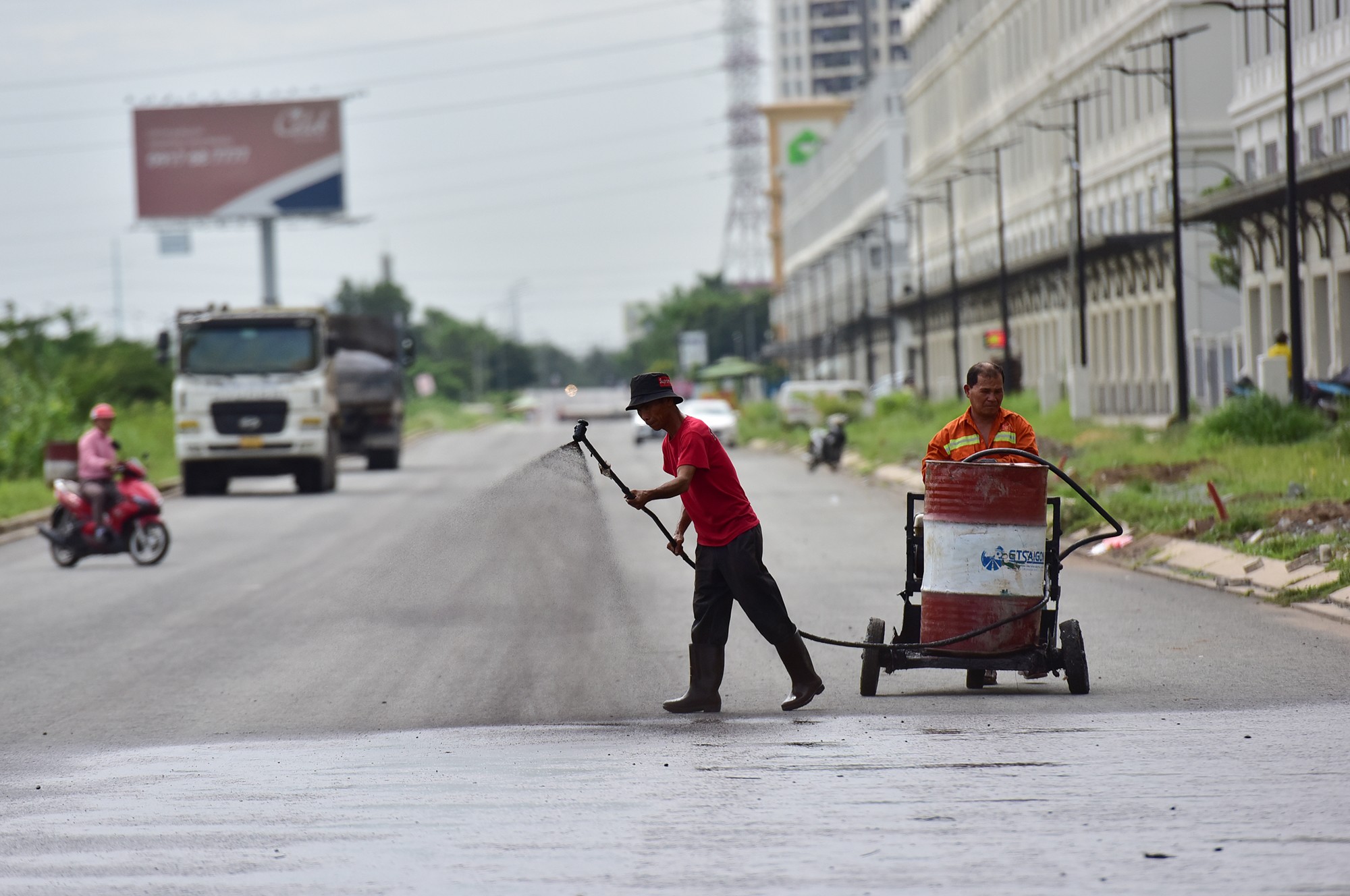 Trong ngày 25/7, nhóm công nhân tưới chất liệu kết dính để thảm lớp nhựa cuối cùng đoạn giao với đường Đỗ Xuân Hợp.
