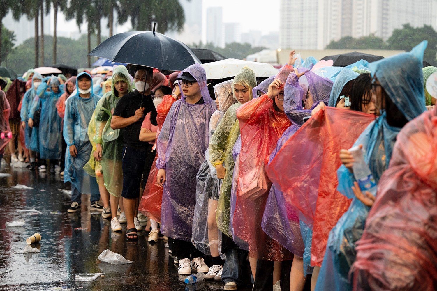 Tại cửa soát vé, người hâm mộ mặc áo mưa đứng xếp hàng để vào trong sân vận động Mỹ Đình.