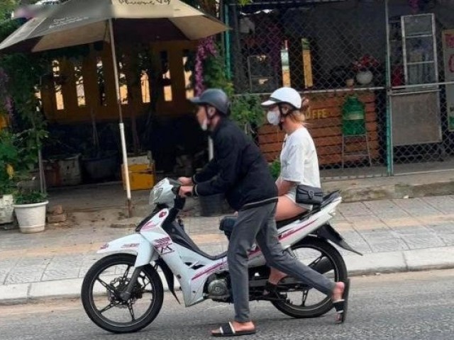 Cô gái ngồi chễm chệ trên xe máy, mặc bạn trai hì hục dắt