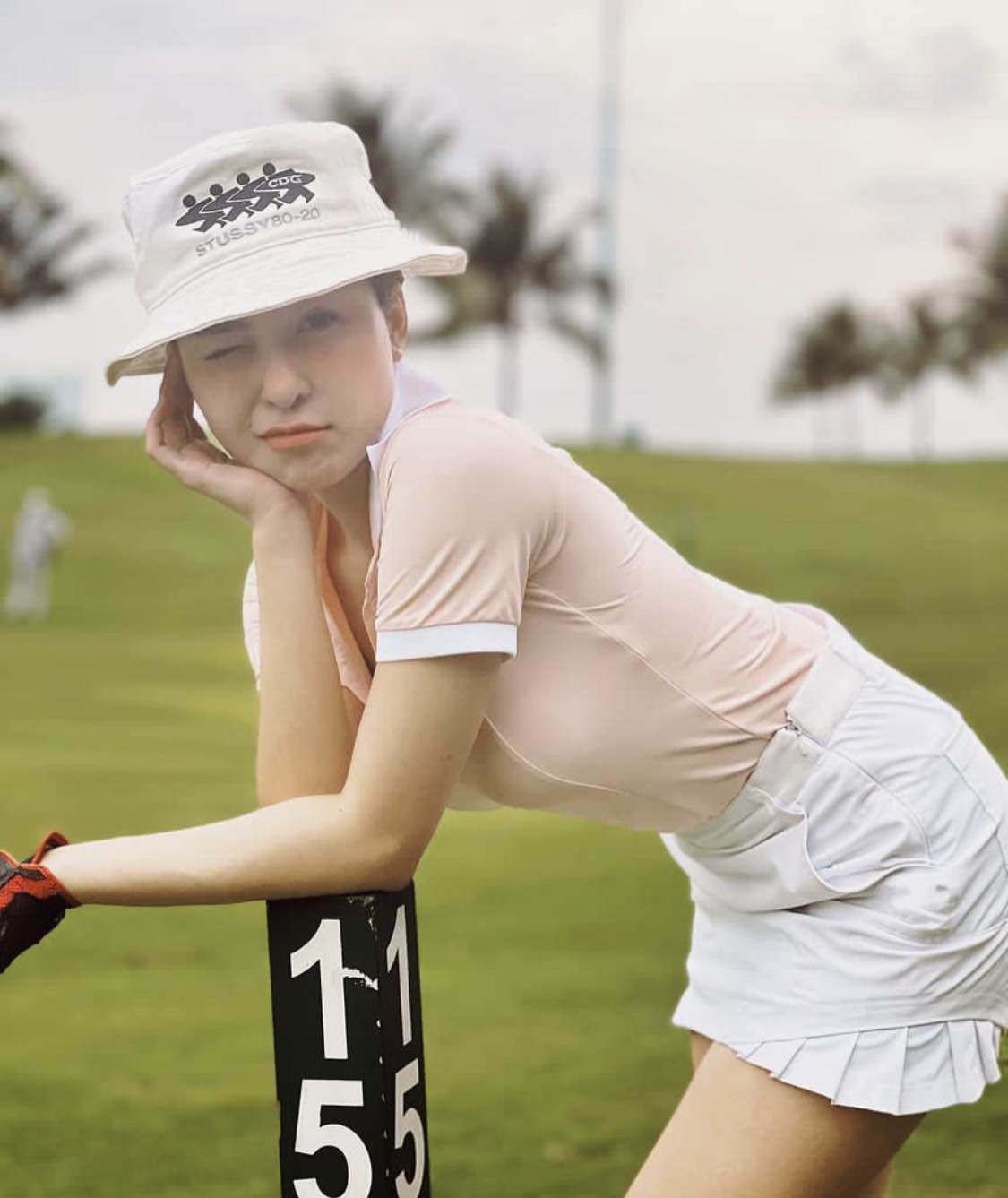 Trâm Anh khoe dáng trên sân golf trong trang phục bao gồm chân váy ngắn và áo polo cộc tay.