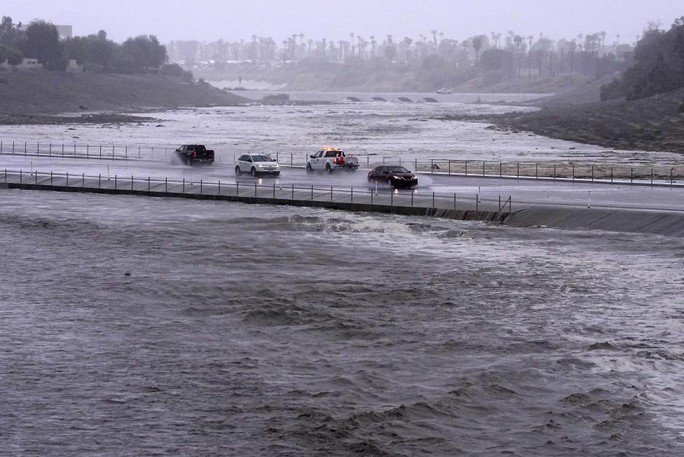 Các phương tiện băng qua lưu vực mà nước lũ gần như đã chạm đến mặt đường hôm 20-8 ở TP Palm Desert, California - Ảnh: AP