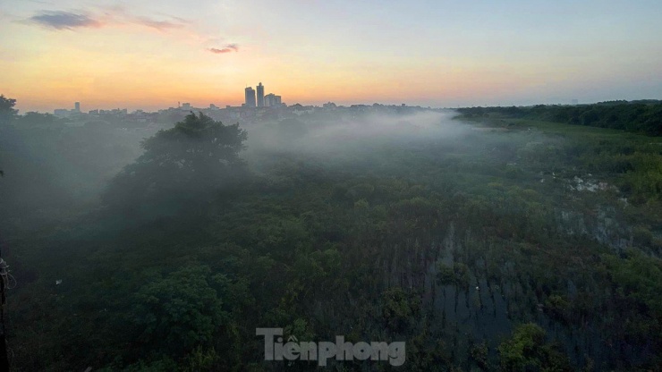 Vào thời điểm mặt trời dần khuất dần sau dãy núi Ba Vì phía xa, những làn sương khói mờ ảo xuất hiện nhiều phía dưới bãi giữa của khu vực chân cầu Long Biên.