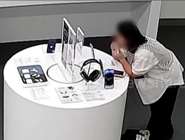 Qiu cắn dây cáp chống trộm để lấy cắp iPhone 14 trong cửa hàng. Ảnh: Newsflare.