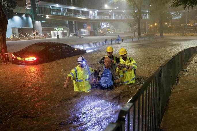 Công nhân thoát nước hỗ trợ một tài xế mắc kẹt do lũ lụt trong trận mưa lớn ở Hồng Kông hôm 8-9. Ảnh: Reuters