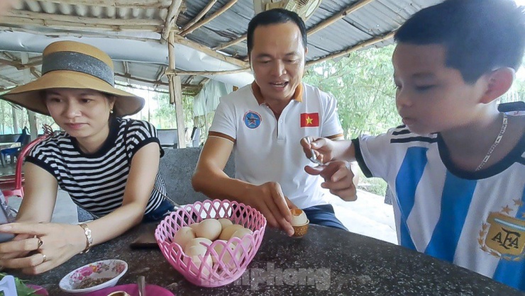 Du khách thưởng thức món trứng luộc ở suối nước nóng Hội Vân. (Ảnh: Trương Định)