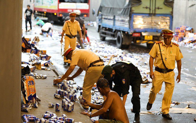 Người dân và cảnh sát giao thông giúp tài xế gom các lon bia còn nguyên vẹn