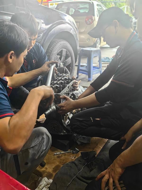 Những người thợ trong nhóm của anh Lâm Louis đang sửa chữa một chiếc xe ô tô cũ.