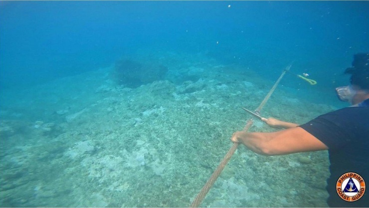 Hình ảnh do Cảnh sát biển Philippines đăng tải cho thấy một người lặn ống thở cắt dây phao của Trung Quốc gần bãi cạn Scarborough. Ảnh: PCG