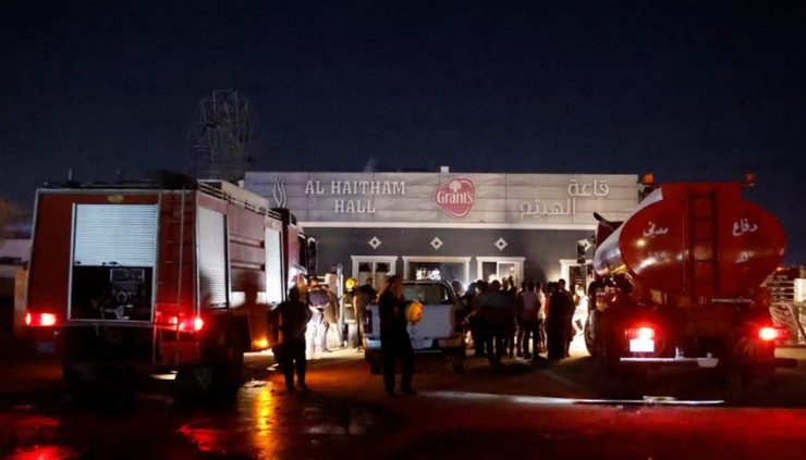 Người dân và lực lượng cứu hỏa tập trung trước hiện trường vụ cháy đám cưới ngày 26-7. Ảnh: REUTERS
