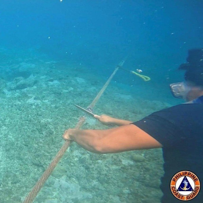 Thành viên lực lượng bảo vệ bờ biển Philippines cắt hàng rào dây phao gần bãi cạn Scarborough ở biển Đông. Ảnh: Lực lượng bảo vệ bờ biển Philippines