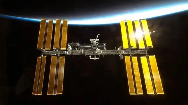 Trạm vũ trụ quốc tế sáng rực trong bầu khí quyển của Trái đất ở phía sau.(Ảnh: NASA)