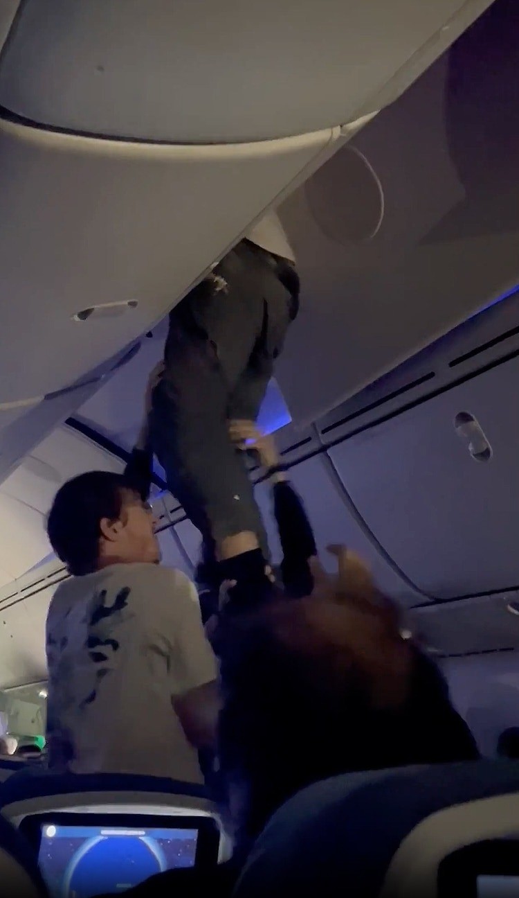 Một hành khách được đưa xuống khỏi tủ để đồ trên cao. Ảnh: Natalia