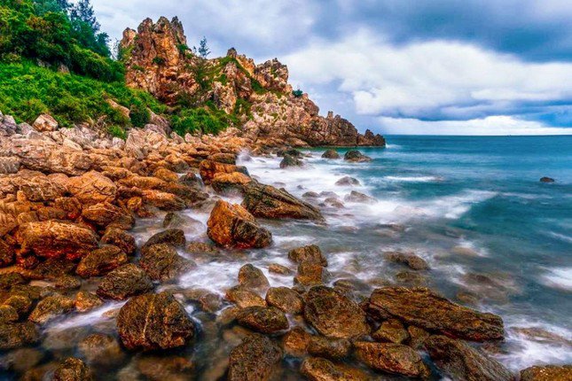 Ngày xưa, học trò khắp nơi thường hay tụ lại đây để lấy loại đá này về làm mực đỏ cho thầy chấm bài nên đến tận bây giờ thì không còn có nhiều loại đá son đỏ này tại Mũi Vi Rồng. Nhưng nếu tỉ mỉ ngắm nhìn thì thỉnh thoảng nhiều khách du lịch vẫn có thể tìm thấy những hòn đá son màu đỏ nằm lẫn trong cát biển. Ảnh: Huỳnh Nguyễn Thành.