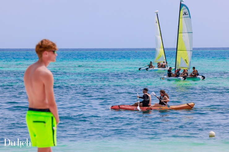 Du khách chèo thuyền kayak và lướt ván buồm khám phá đại dương.
