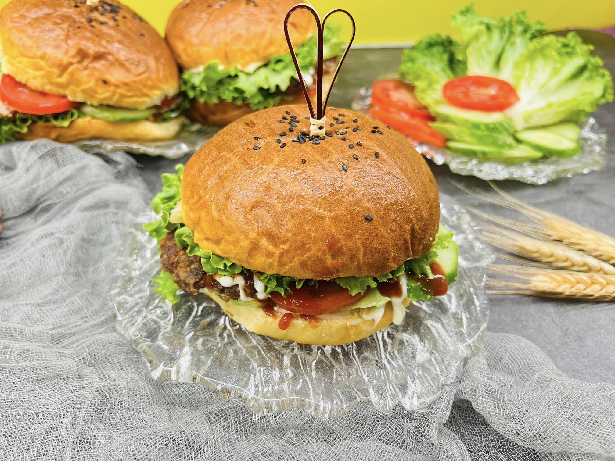 Cuối cùng là khâu trang trí và hoàn thiện hamburger: Lấy 1 chiếc vỏ bánh bổ đôi rồi phết sốt mayonnaise trong lòng 2 mặt, tiếp đó thêm rau xà lách, dưa chuột thái lát mỏng và cà chua, đặt miếng thịt bò và&nbsp;1 lát phô mai rồi lại xếp rau cà chua lên trên, cuối cùng đậy phần còn lại của miếng bánh lên trên cùng.