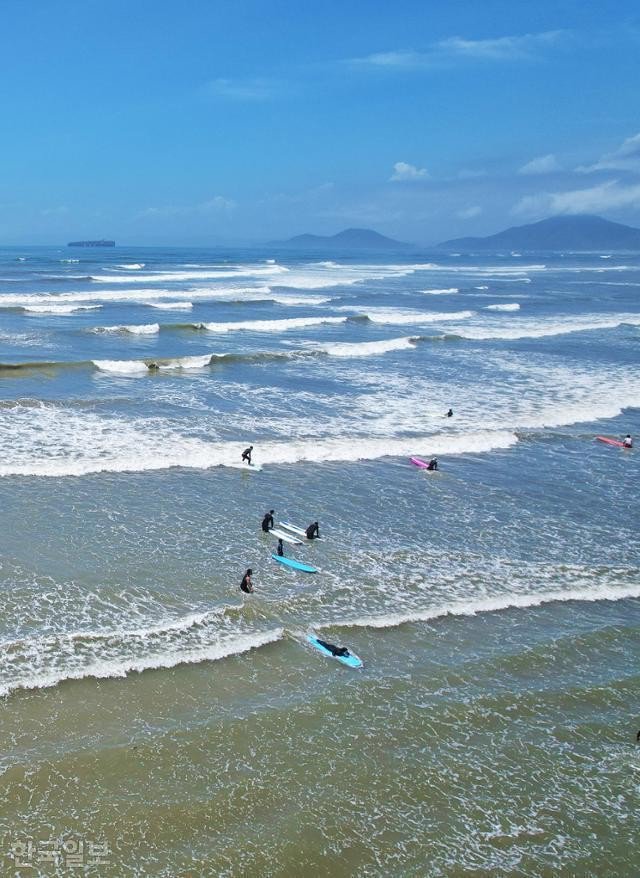 Du khách lướt sóng tận hưởng những con sóng ở bãi biển Dadaepo, Busan. Ảnh: Choi Heung-soo.