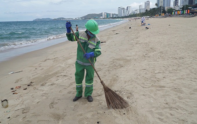 Nhân viên môi trường dọn dẹp dầu vón cục trên bãi biển Nha Trang. Ảnh: Bùi Toàn