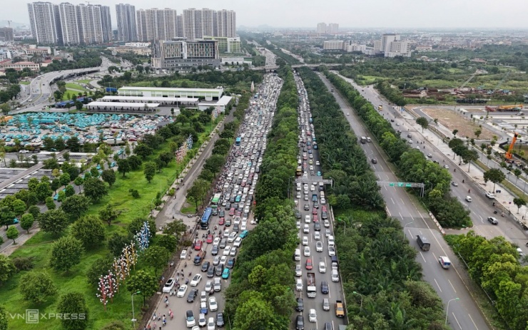 Sáng 9/9, đại lộ Thăng Long bị ùn tắc nhiều giờ kéo dài hơn 10 km từ khu đô thị An Khánh hướng về trung tâm Thủ đô. Sau bão, nhiều cây xanh trên đường bị nghiêng đổ, lô cốt công trình đầu đường Lê Quang Đạo (quận Nam Từ Liêm).