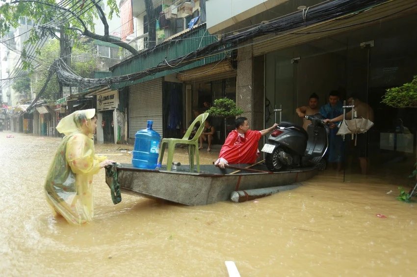 Lực lượng chức năng hỗ trợ người dân di chuyển tài sản lên cao, hạn chế tổn thất do mưa bão, ngập lụt gây ra. Ảnh: PHI HÙNG