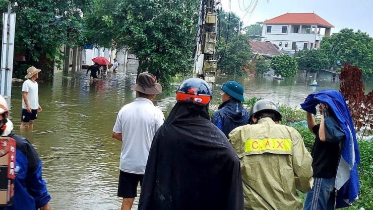 Một số đoạn đường tại Thạch Thất ngập sâu, học sinh nhờ sự hỗ trợ của lực lượng công an để đi qua điểm ngập tới trường. (Ảnh: VNN).