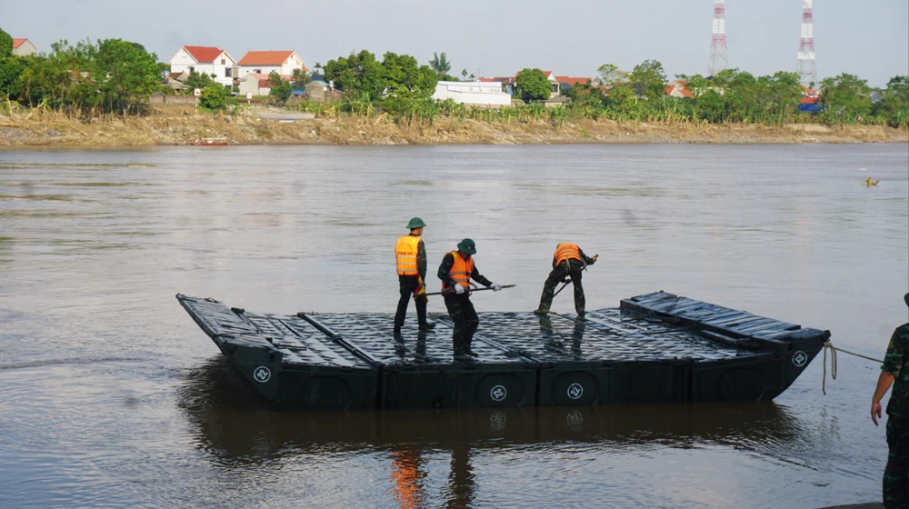 Chiều nay, 28-9, đông đảo cán bộ chiến sĩ của Lữ đoàn 249 - Binh chủng Công binh cùng nhiều phương tiện, máy móc được huy động để lần lượt thả các đốt phao dã chiến xuống sông Hồng, cách không xa cầu Phong Châu bị sập 9-9. Ảnh: XUÂN NGUYỄN.