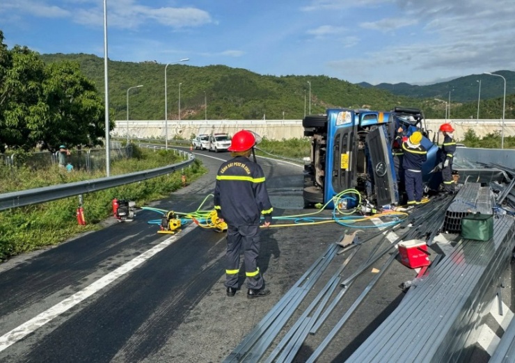 Hiện trường vụ tai nạn xe tải lật nghiêng trên mặt đường, hàng trăm thanh thép hộp rơi vãi.