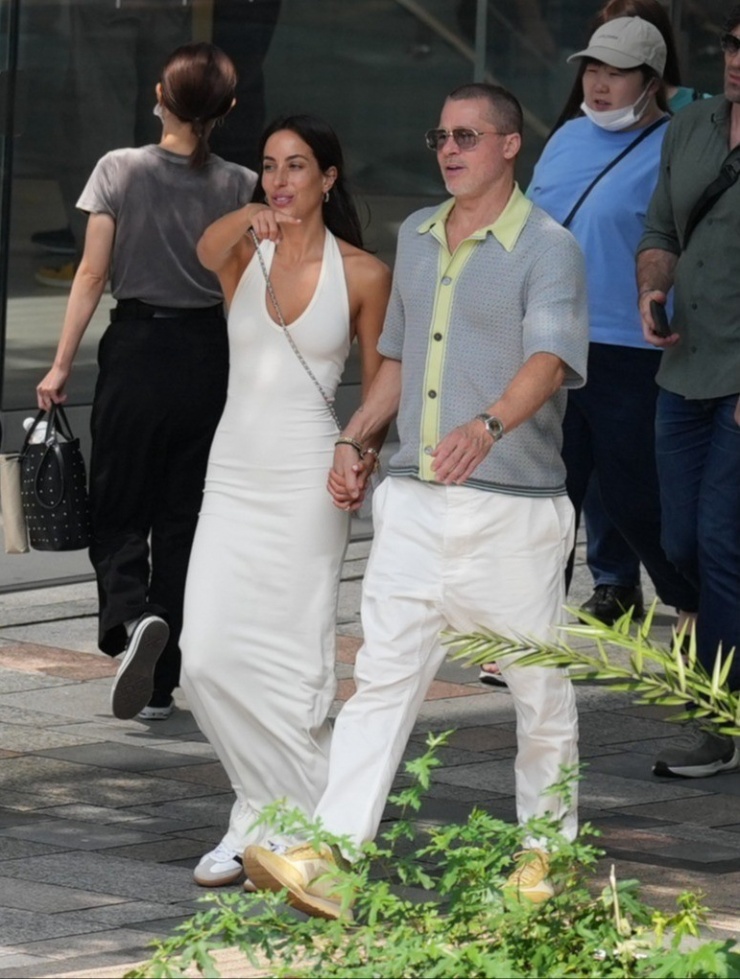 Brad Pitt và bạn gái đi mua sắm trên đường phố Tokyo dịp tài tử quảng bá phim F1 ở đây cuối tháng 6. Cả hai cùng chọn trang phục màu trắng, giày sneakers để đi bộ cho thoải mái. Ảnh: SplashNews