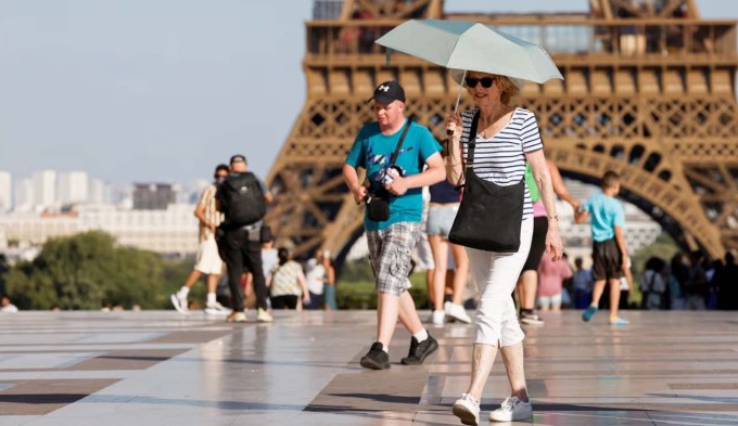 Du khách dùng ô che nắng để tránh nắng nóng khi đến thăm tháp Eiffel, Paris, Pháp hôm 30/6. Ảnh: AFP