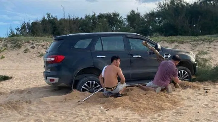Ô tô bảy chỗ bị mắc cạn trên bãi biển khu vực tháp Nghinh Phong, phường Bình Kiến. Ảnh cắt từ clip.
