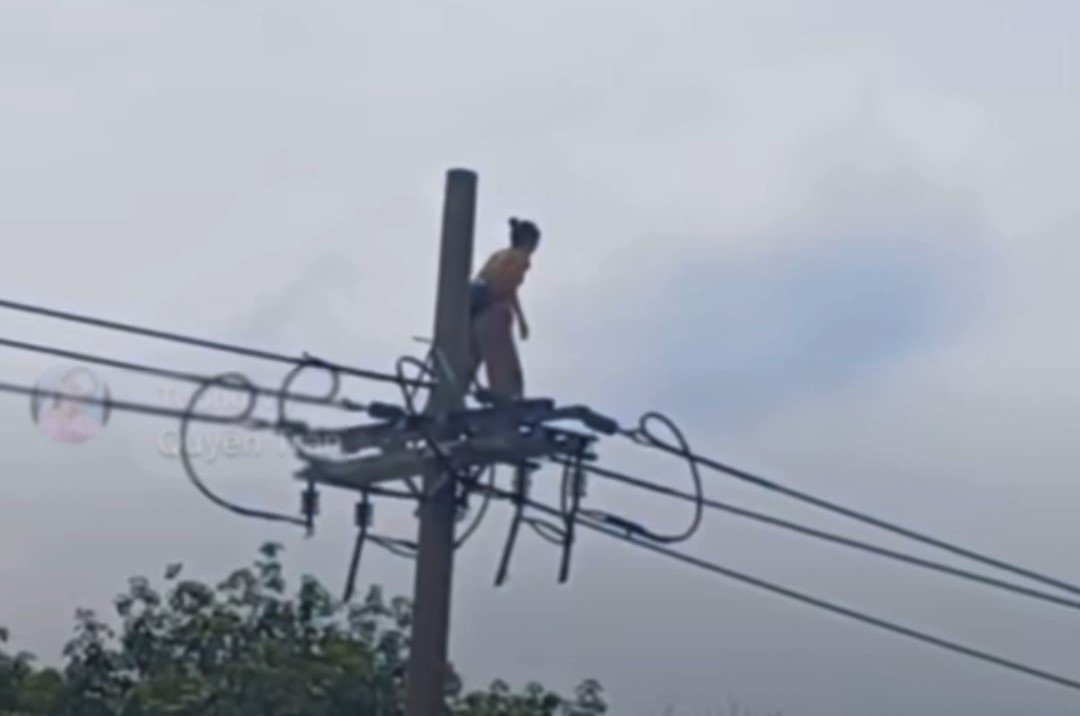 Người phụ nữ đu trên đường dây điện hạ thế.