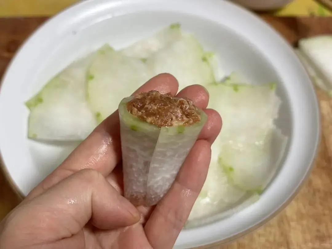 Lấy từng lát bí đao cuộn tròn lại như hình ống, nhét thịt băm vào giữa, làm cho tới khi hết nguyên liệu.