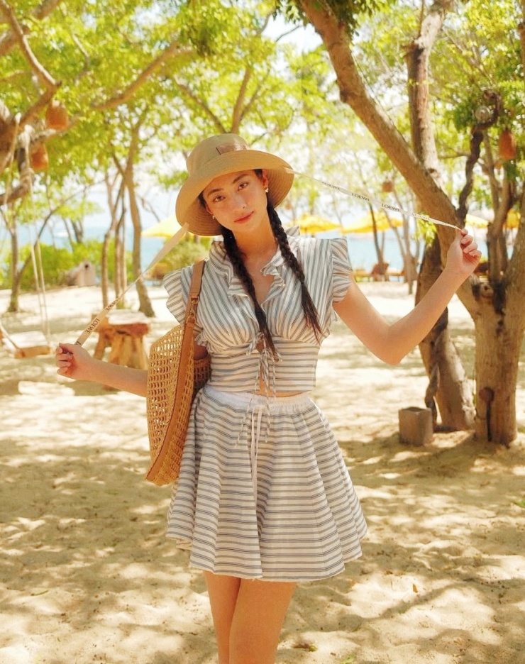 Họa tiết kẻ - một trong những xu hướng hot của Xuân Hè 2025 - được Lương Thùy Linh lựa chọn khi đi nghỉ dưỡng. Hoa hậu dùng mũ Loewe và túi Saint Laurent giúp tăng vẻ sang trọng.