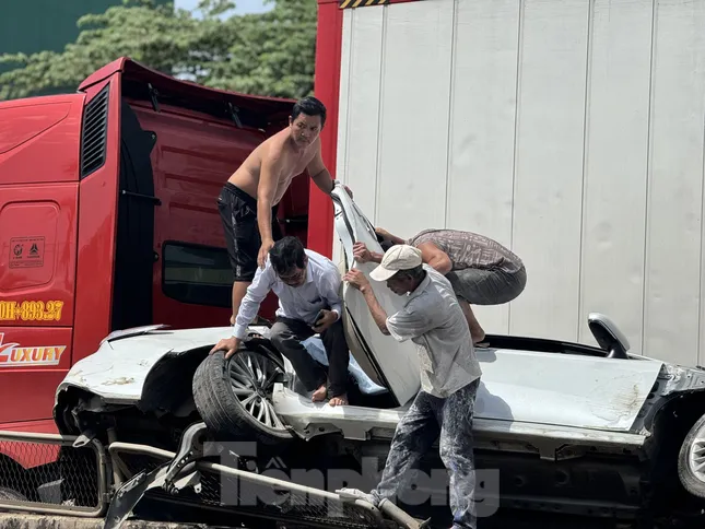 Người dân hỗ trợ các nạn nhân bên trong xe ô tô con ra ngoài. Ảnh: Nguyễn Ngọc