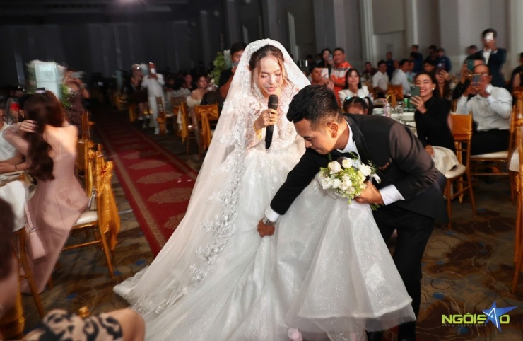Hùng Thuận nâng váy cưới, giúp vợ bước lên sân khấu.