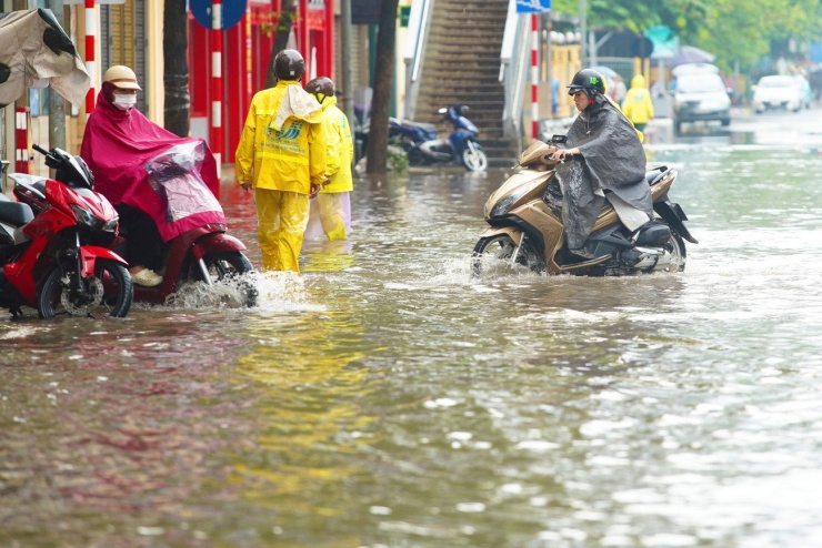 Nước ngập tràn qua vỉa hè, phương tiện vừa đi vừa dò dẫm.