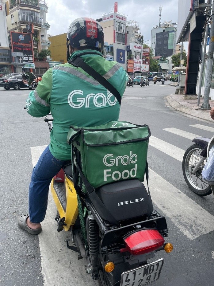 Một tài xế xe công nghệ giao hàng bằng xe điện tại TP HCM