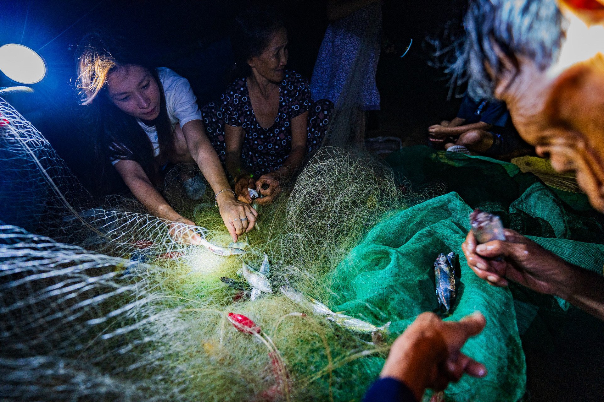 Vợ chồng anh Nhật theo chủ homestay đi đánh cá, gỡ lưới. Ảnh: Nguyễn Hồng Nhật