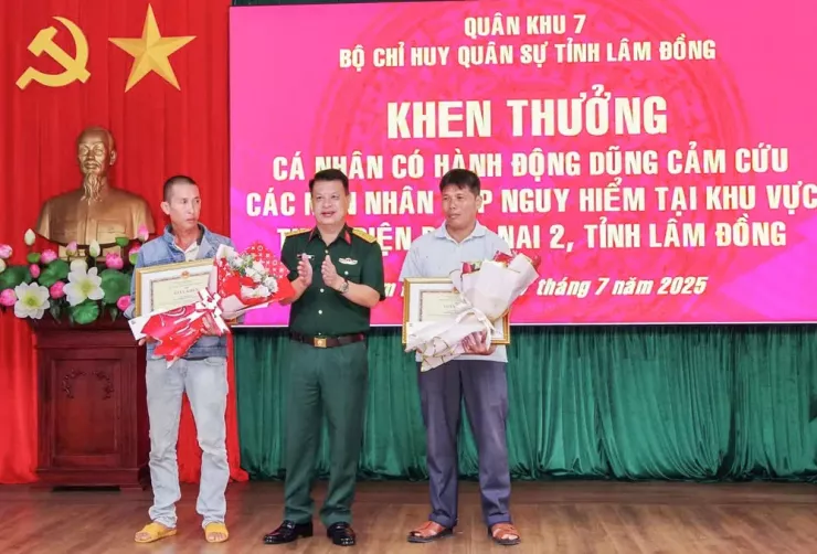 Đại tá Đinh Hồng Tiếng, Chỉ huy trưởng Bộ Chỉ huy Quân sự tỉnh Lâm Đồng, trao bằng khen, hoa cho hai cá nhân đã cứu ba người, hôm 16-7. Ảnh: TRÙNG DƯƠNG
