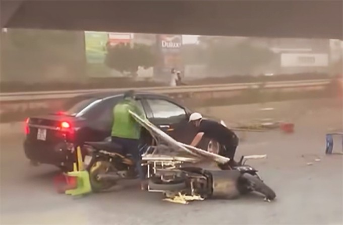 Người đi xe máy bị gió thổi ngã trên đường Nguyễn Xiển, thuộc vành đai 3, Hà Nội.