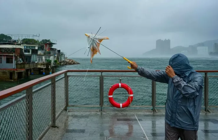 Một người đàn ông bị gió quật sập dù khi đang đi trong bão tại khu Lei Yue Mun. Ảnh: Sam Tsang/ SOUTH CHINA MORNING POST