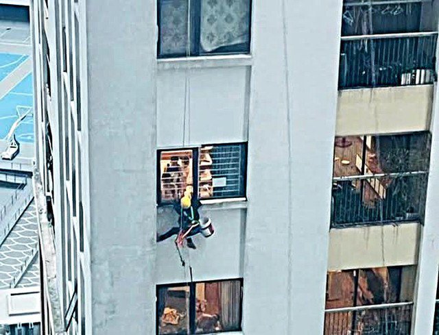 Hình ảnh thợ sơn bám vào cửa sổ căn hộ chung cư Vinaconex 2 trong cơn dông lốc chiều 19/7.