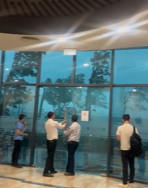 Chị Thảo chỉ kịp chụp biển số xe của người tài xế tốt bụng. Bên phải là hình ảnh mưa gió lớn phía trước cửa tòa nhà mà chị Thảo ghi lại khi đã trở về an toàn
