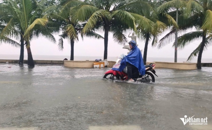 Người đàn ông đi xe máy trên đường ngập sâu. Ảnh: Lê Dương