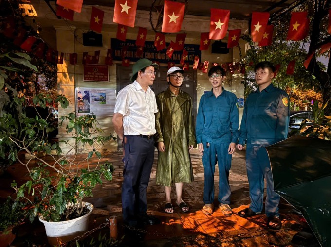 Chủ tịch UBND phường Giảng Võ Cồ Như Dũng (áo trắng) cùng dân quân trao đổi phương án chốt trực bảo đảm an ninh, an toàn khu chung cư cũ khi người dân di dời tạm. Ảnh: Hoàng Phong