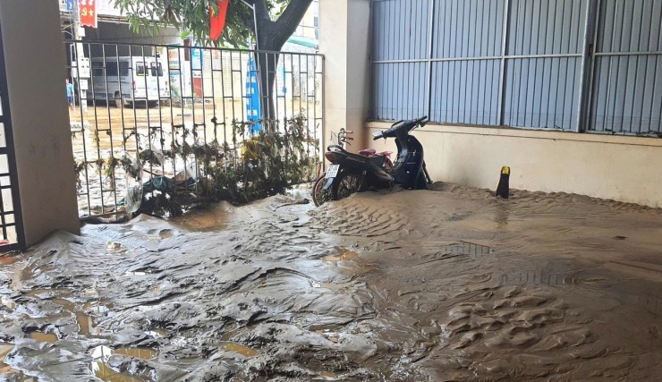 Chiếc xe máy dựng trong sân nhà bị đất cát của trận lũ vùi lấp gần một nửa thân xe.