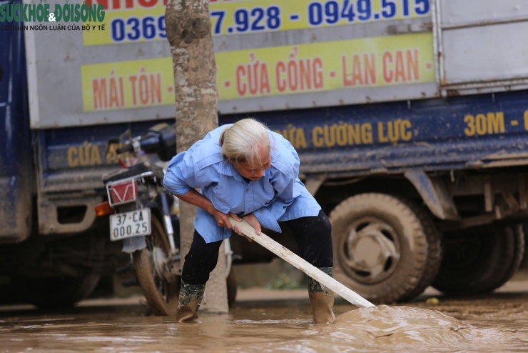 Tại thôn Tiến Thành, xã Con Cuông, một cụ bà lom khom gồng người đầy bùn ra khỏi sân.