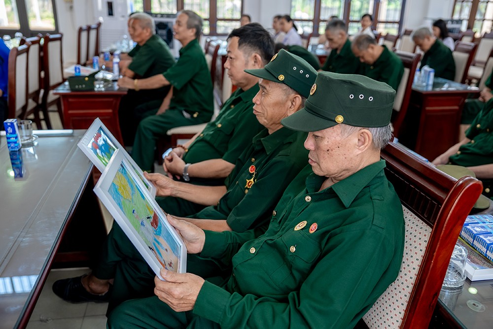 Các bác cựu chiến binh chăm chú đọc những dòng chữ nhỏ, được các em gửi kèm trong mỗi bức tranh (Ảnh: Duy Cường).