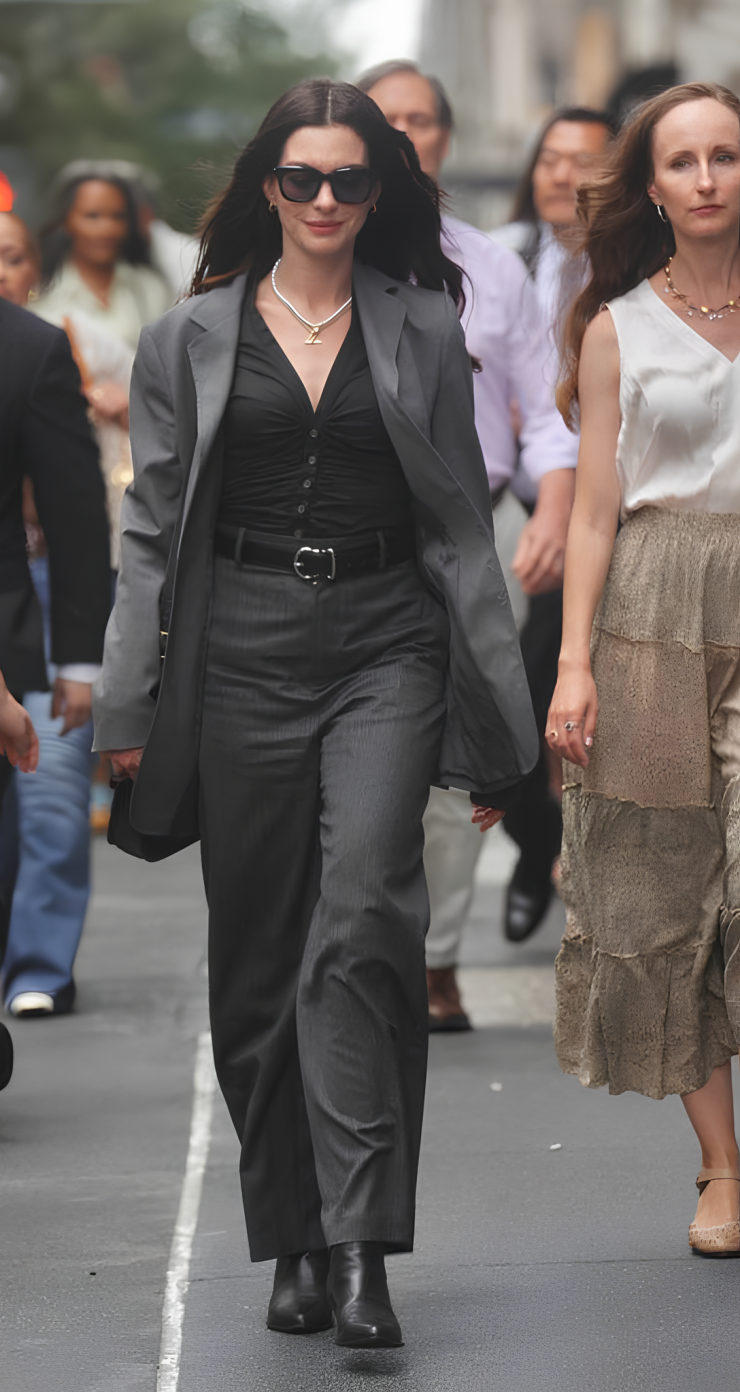Anne Hathaway năng động và hiện đại khi diện set đồ vest màu xám, xách cặp Coach 895 USD, mang boots Golden Goose, đeo vòng cổ kim cương Jemma Wynne 14.910 USD.