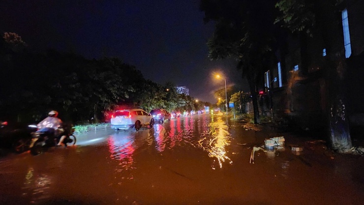 Trên đại lộ Thăng Long, nước ngập tràn mặt đường, các phương tiện phải men theo mép đường để di chuyển.